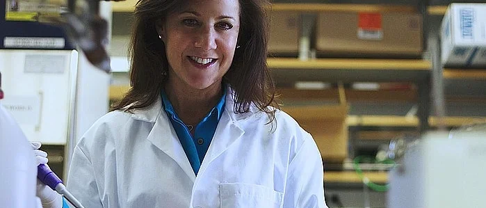A researcher in a white lab coat work in her lab.
