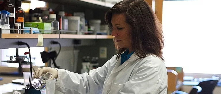 A researcher in a white lab coat works in the lab.