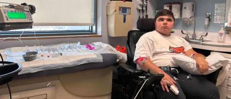 Young patient with Duchenne Muscular Dystrophy sitting in clinic chair. 