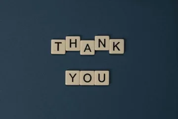 Wooden lettered tiles are arranged to read "thank you."