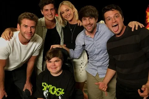 Hunger Games stars and interviewers stand around Dylan Miceli-Nelson. 