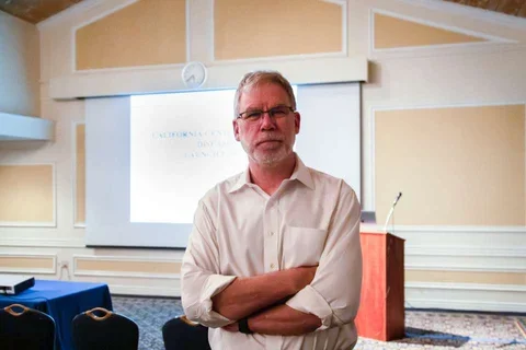 Dr. Stanley Nelson standing with arms crossed in front of a classroom.