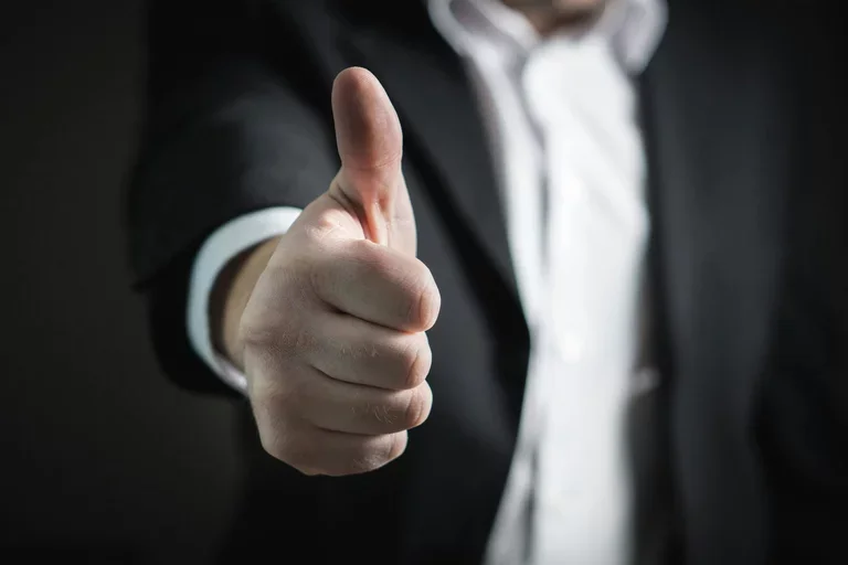 An arm is extended outward with a hand giving a thumbs up.
