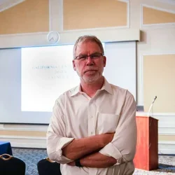 Dr. Stanley Nelson standing with arms crossed in front of a classroom.