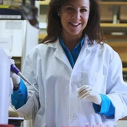 A researcher in a white lab coat work in her lab.