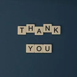 Wooden lettered tiles are arranged to read "thank you."